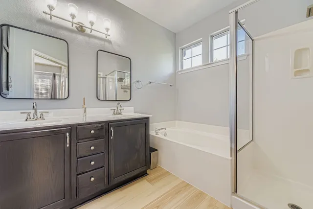 a bathroom with a tub a double vanity sink and mirror