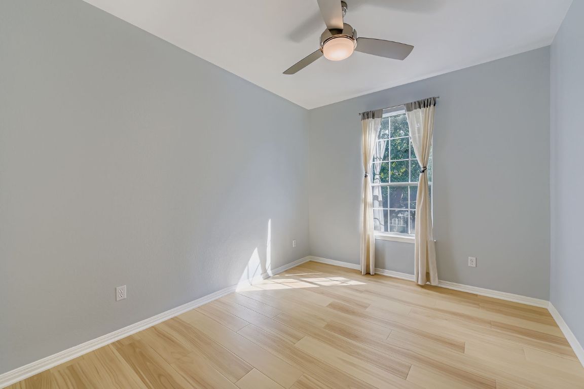 8518 Cahill Drive, Unit 20 Austin, TX 78729 - Photo 18 of 36 an empty room with wooden floor chandelier fan and windows