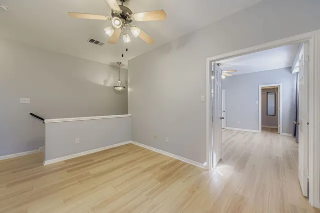 a view of a room with wooden floor and chandelier fan