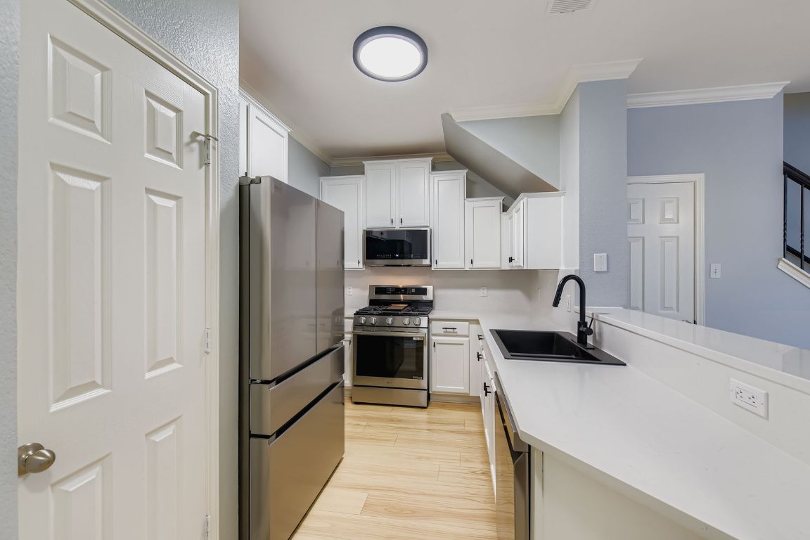 8518 Cahill Drive, Unit 20 Austin, TX 78729 - Photo 10 of 36 a kitchen with stainless steel appliances a refrigerator a stove a sink and a refrigerator