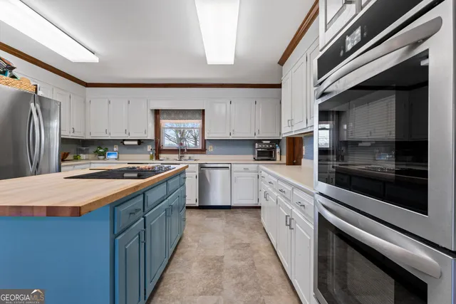 a large kitchen with stainless steel appliances kitchen island granite countertop a stove a sink and a refrigerator