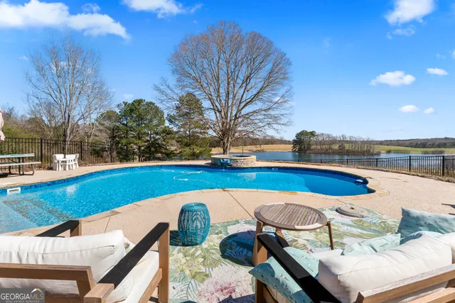 a view of swimming pool with lounge chair and dinning table under an umbrella