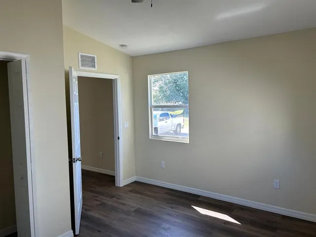 a view of an empty room with wooden floor and a window