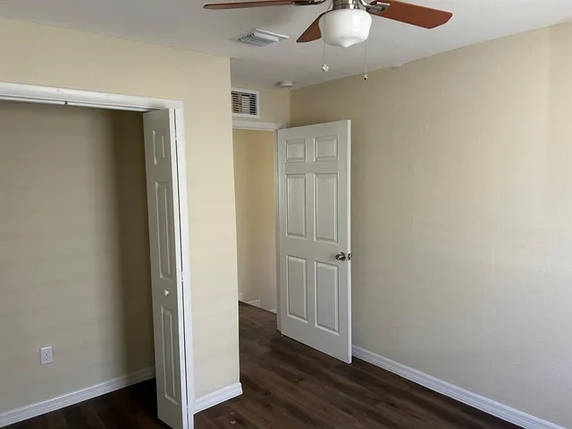 an empty room with wooden floor closet and windows