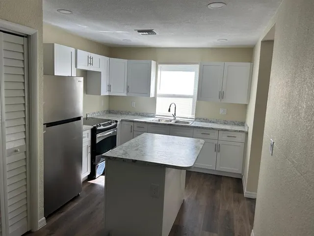 a kitchen with kitchen island granite countertop a sink cabinets and stainless steel appliances