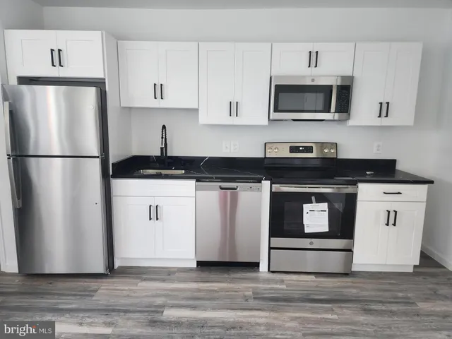 a kitchen with white cabinets white stainless steel appliances and sink
