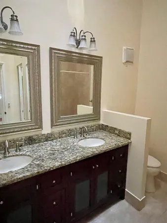 a bathroom with a granite countertop sink a toilet and mirror