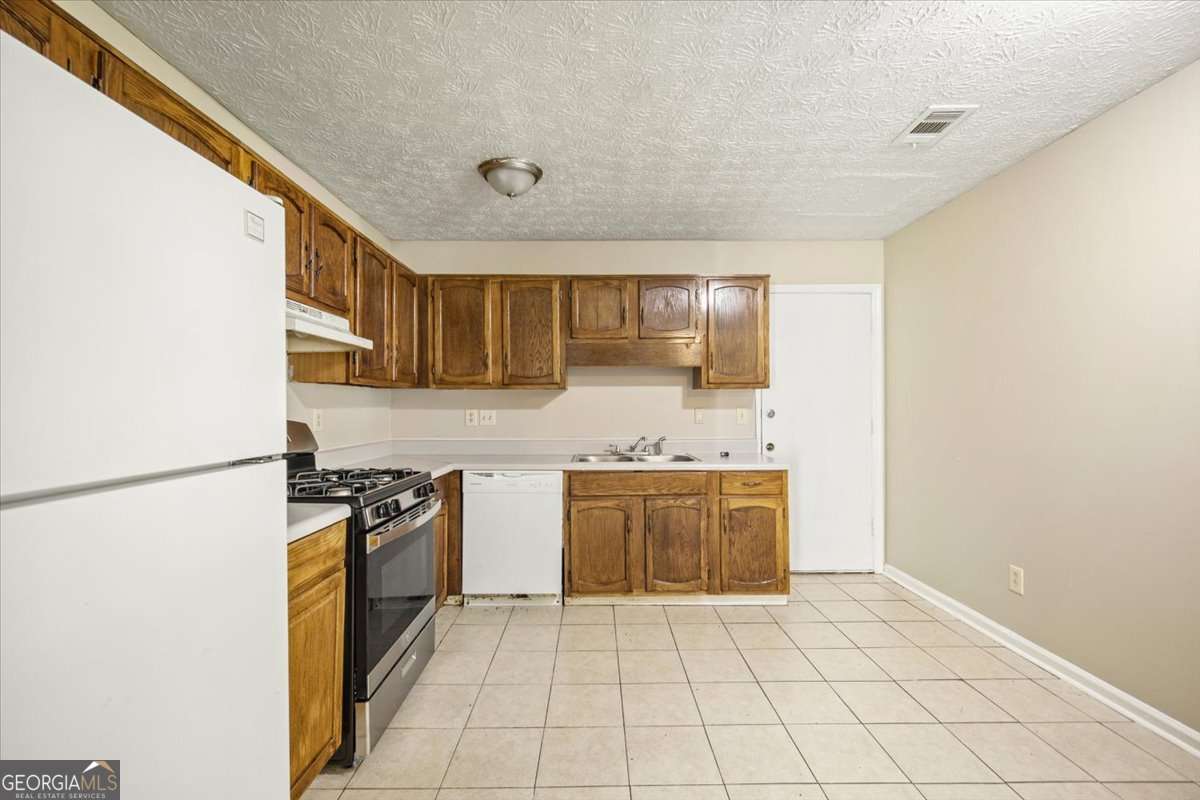 5426 Martins Crossing Road Stone Mountain, GA 30088 - Photo 11 of 26 a kitchen with stainless steel appliances granite countertop a stove a sink and a refrigerator