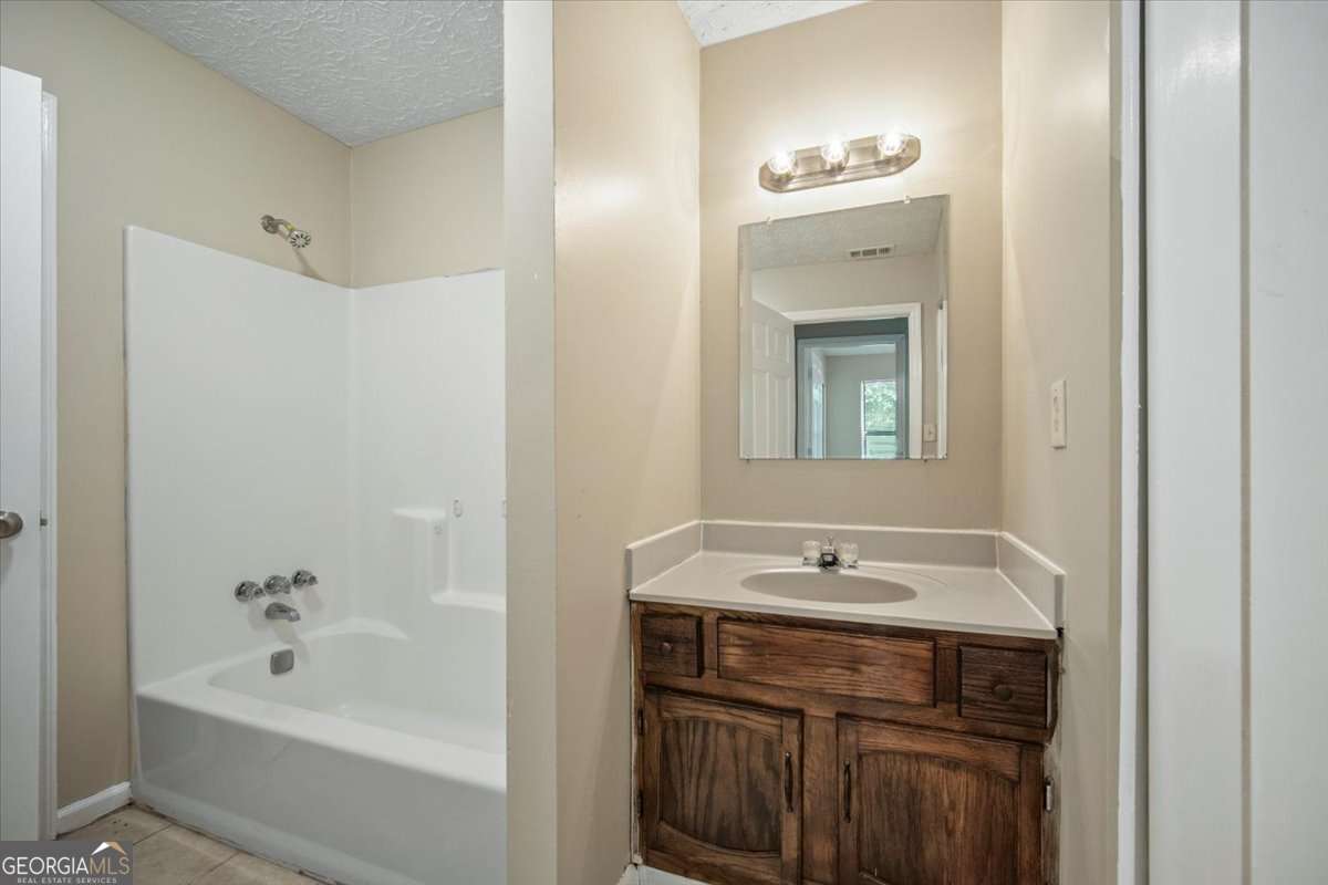5426 Martins Crossing Road Stone Mountain, GA 30088 - Photo 15 of 26 a bathroom with a tub sink and mirror
