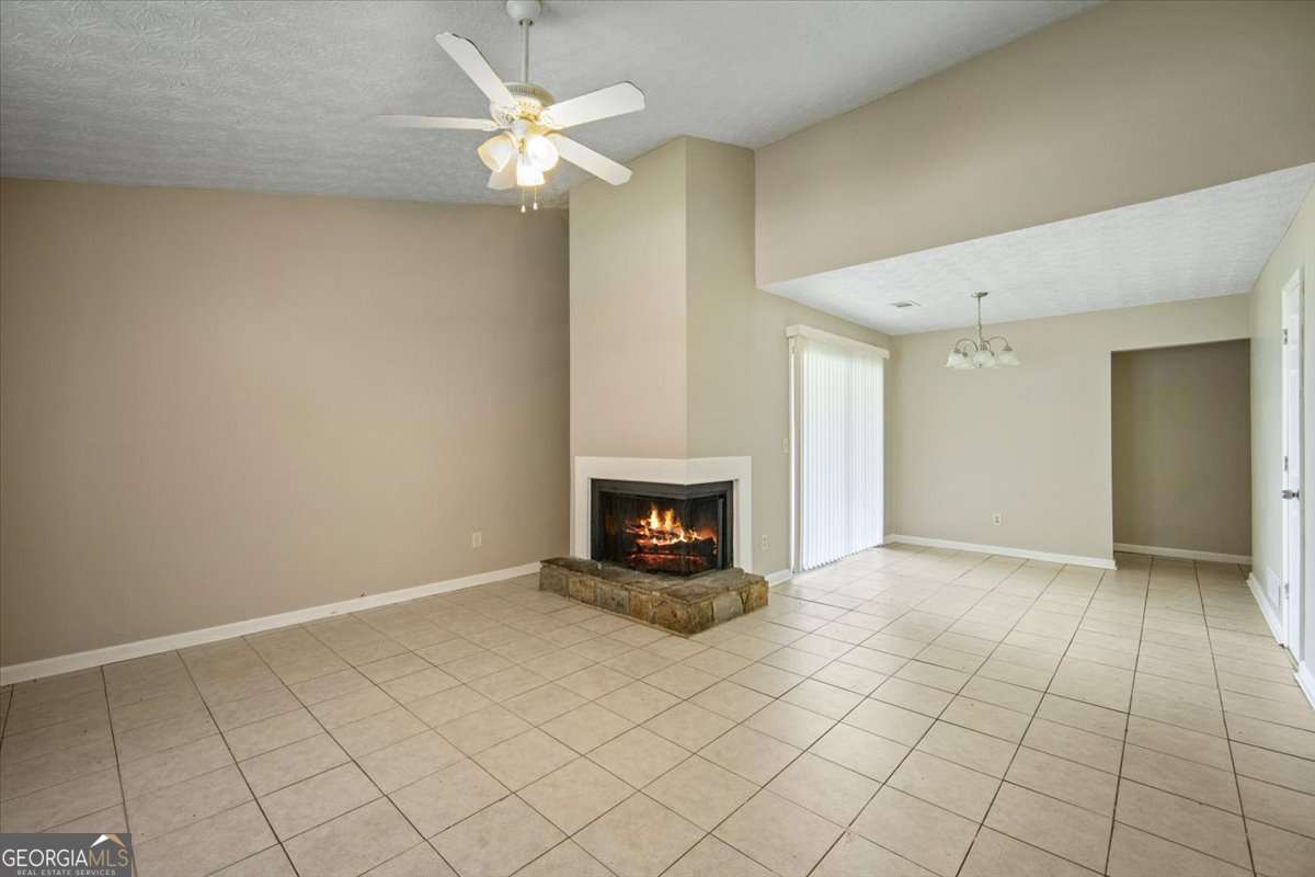 5426 Martins Crossing Road Stone Mountain, GA 30088 - Photo 4 of 26 an empty room with fireplace and fan