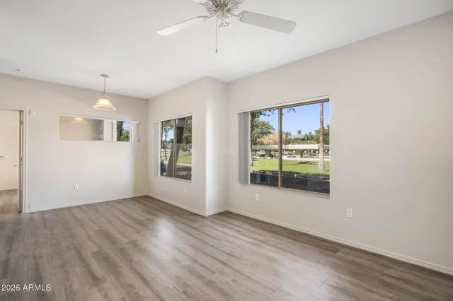 a view of an empty room with a window and wooden floor