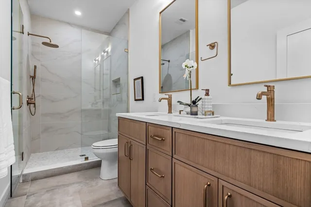 a bathroom with a double vanity sink toilet and shower