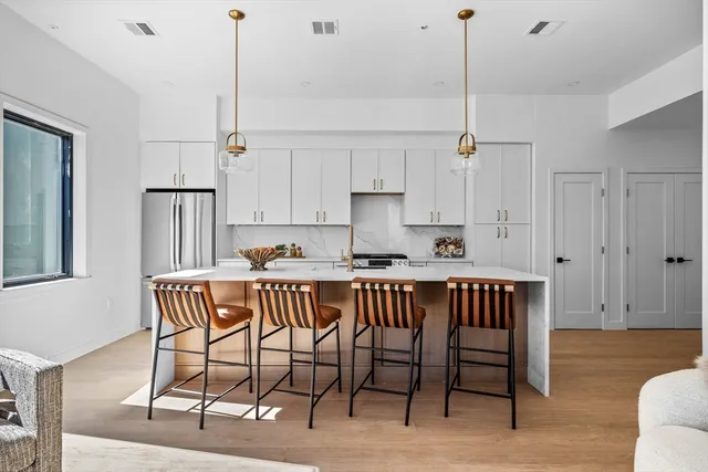 a view of kitchen with stainless steel appliances granite countertop dining table chairs sink and cabinets