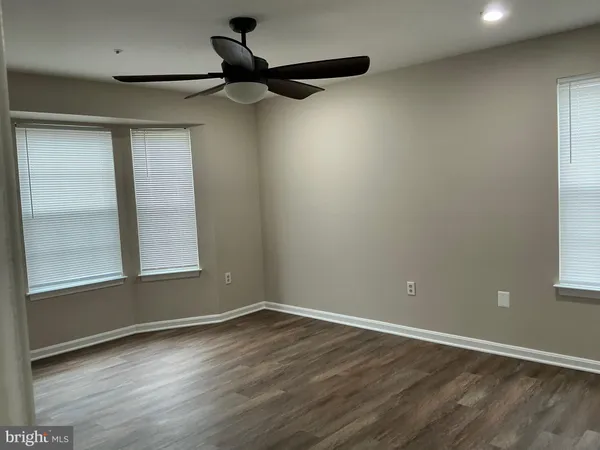 an empty room with wooden floor closet and windows