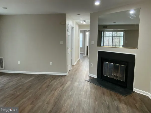 an empty room with wooden floor fireplace and windows