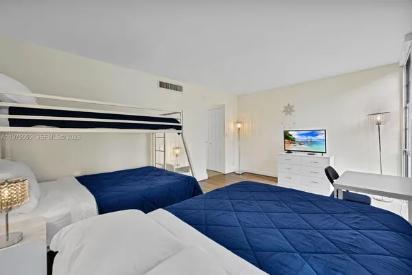 a bedroom with two beds and a lamp on dresser