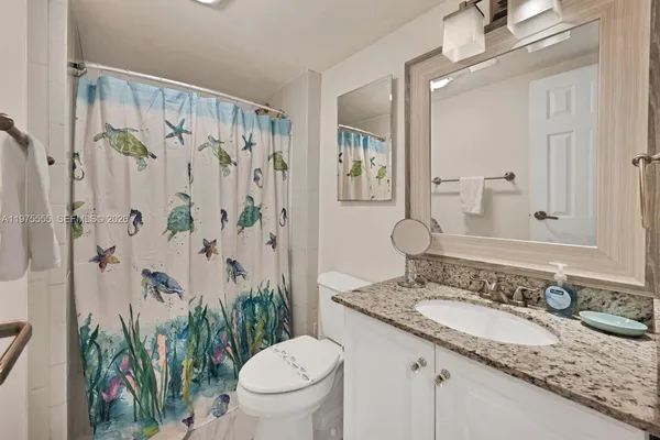 a bathroom with a granite countertop sink a toilet and a mirror