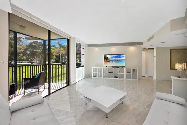 a living room with furniture a flat screen tv and a floor to ceiling window
