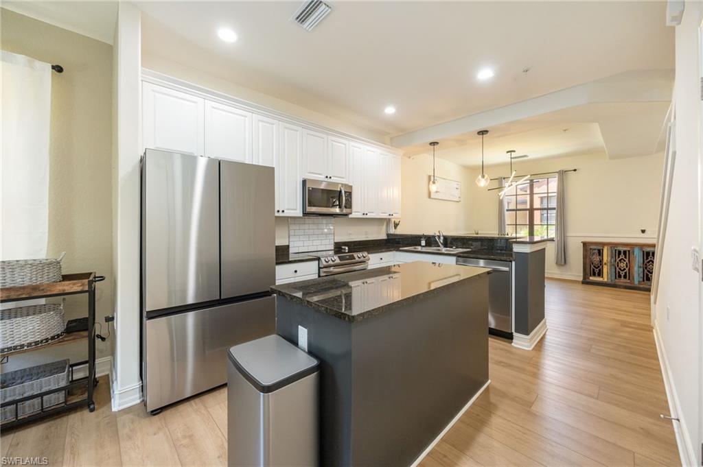 9128 Delano Street, Unit 892 Naples, FL 34113 - Photo 4 of 49 a kitchen with stainless steel appliances granite countertop a refrigerator a stove and a wooden floors