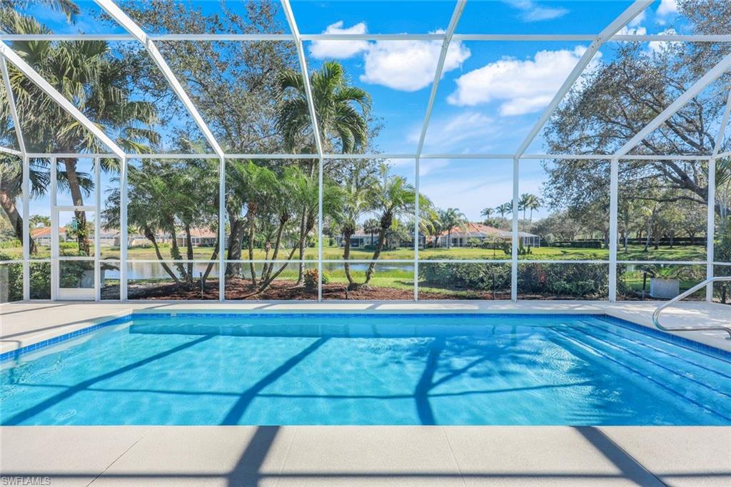 3108 Dominica Way Naples, FL 34119 - Photo 25 of 39 Screen-enclosed heated saltwater swimming pool featuring a tiled waterline, integrated steps, and a surrounding patio deck