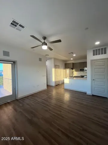 an empty room with wooden floor ceiling fan and windows