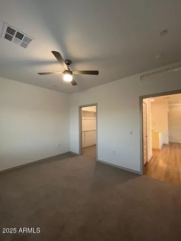 an empty room with a ceiling fan and windows