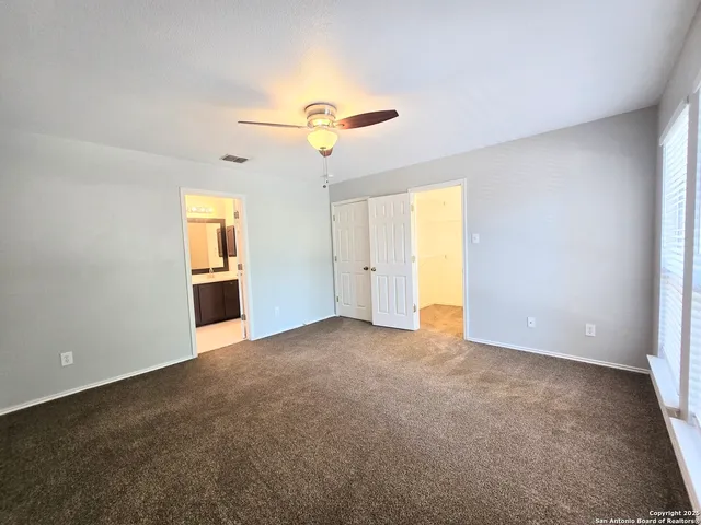 an empty room with windows and ceiling fan