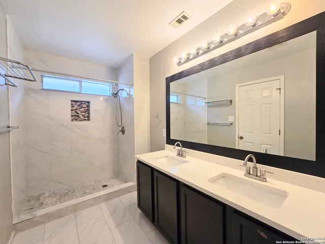 a bathroom with a double vanity sink mirror and shower
