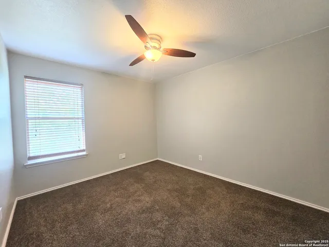 an empty room with a window and ceiling fan