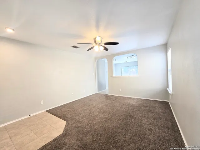 an empty room with a window and a fan