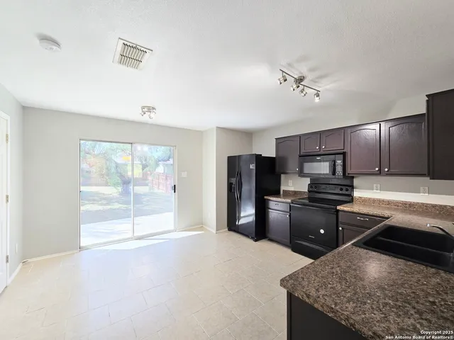 a kitchen with stainless steel appliances kitchen island granite countertop a refrigerator stove top oven and sink