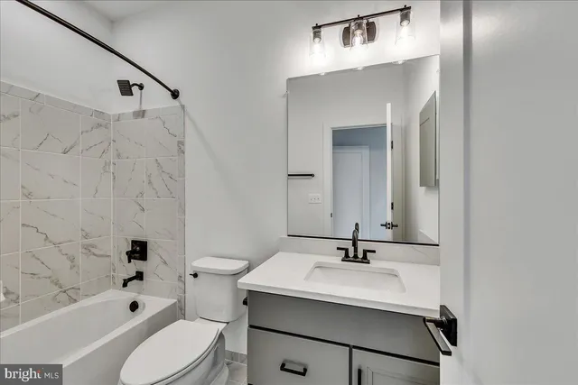 a bathroom with a bathtub shower sink vanity and toilet