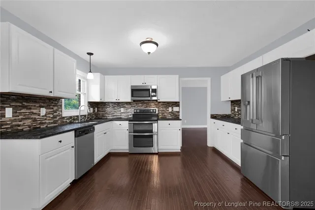 a kitchen with granite countertop a refrigerator stove top oven and sink
