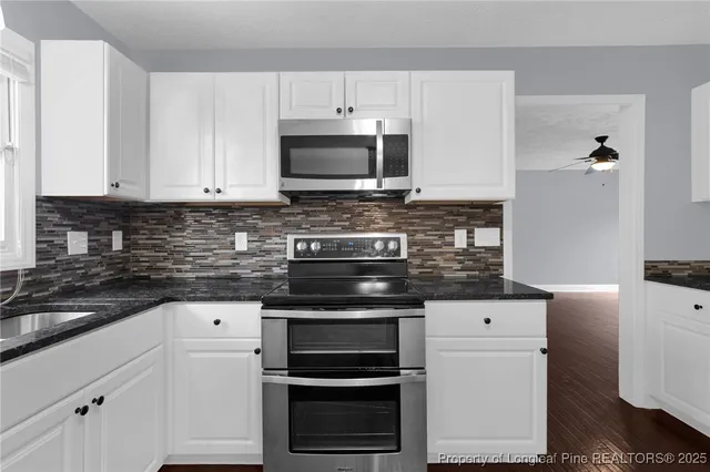 a kitchen with granite countertop a stove and a microwave