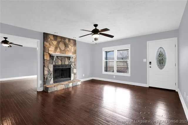 a view of an empty room with wooden floor fireplace and a window
