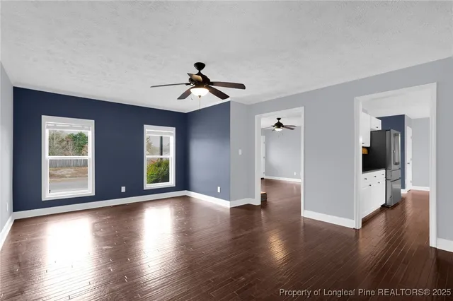 a view of an empty room with window and wooden floor