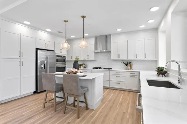 a kitchen with stainless steel appliances granite countertop a stove a sink a refrigerator and a dining table with wooden floor