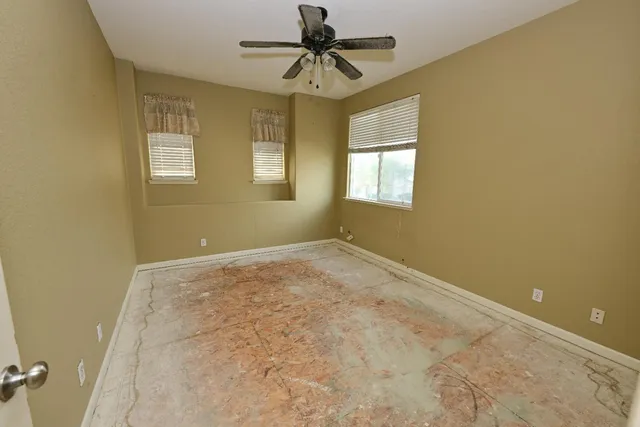 an empty room with a window and a ceiling fan