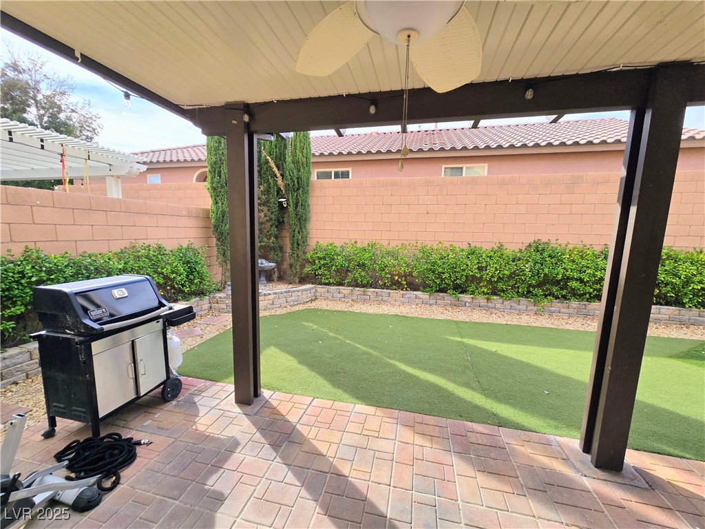 10855 Casco Bay Street Las Vegas, NV 89179 - Photo 49 of 64 Fenced backyard with an area to practice putting, a grill, a ceiling fan, and a patio