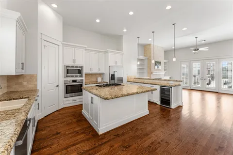 a large kitchen with stainless steel appliances granite countertop a large center island a stove a refrigerator a sink and a oven