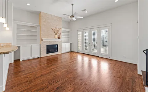 an empty room with wooden floor fireplace and windows