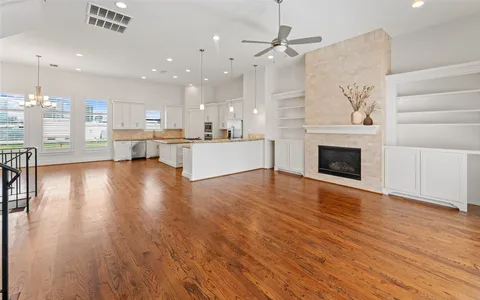 a living room with stainless steel appliances furniture a fireplace and wooden floor