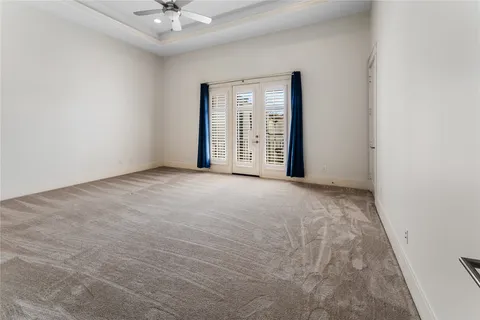 an empty room with chandelier fan and windows