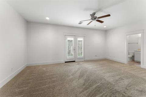 an empty room with chandelier fan and windows