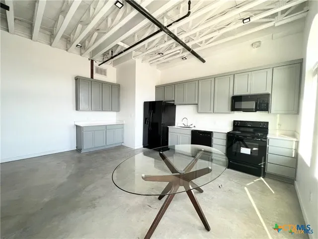 a kitchen with stainless steel appliances a refrigerator a stove a sink dishwasher and white cabinets with wooden floor