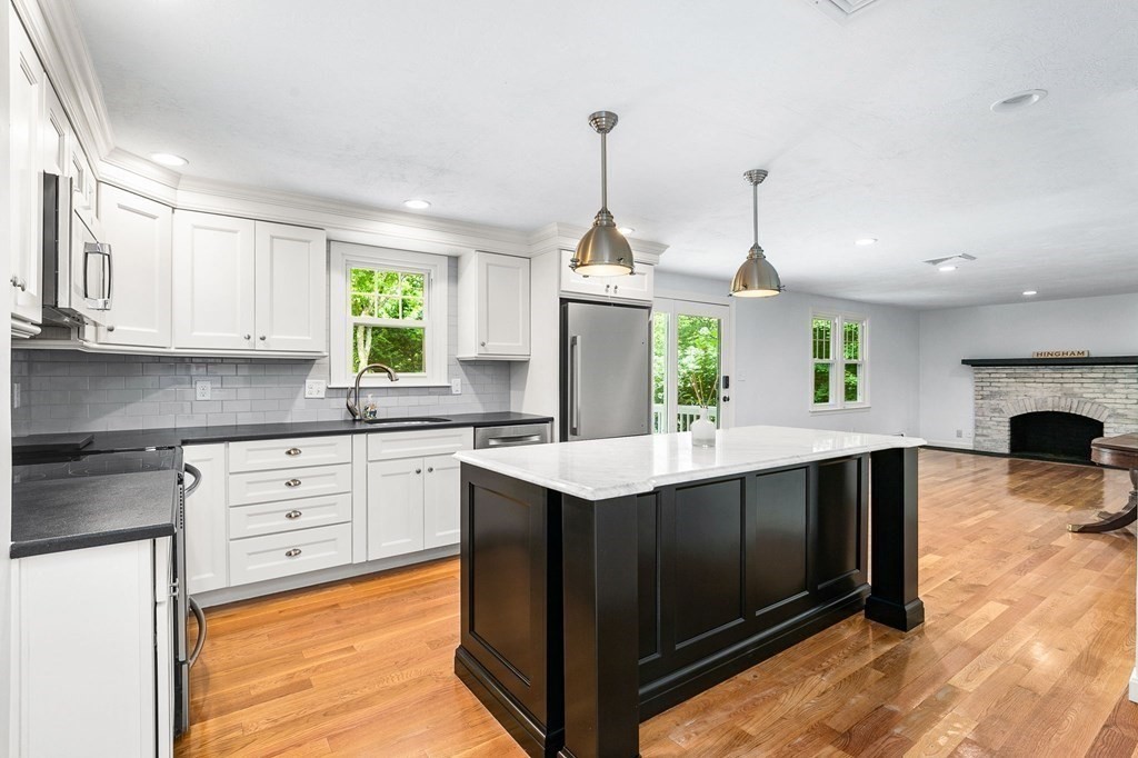 a kitchen with kitchen island granite countertop a stove a sink dishwasher and cabinets with wooden floor