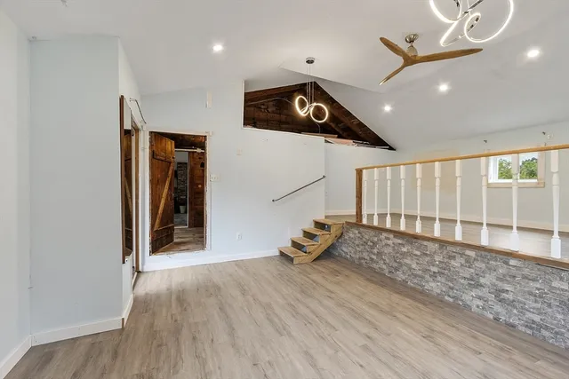 wooden floor in an empty room with stairs and a ceiling fan