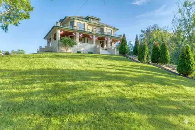 a front view of house with yard and trees in the background