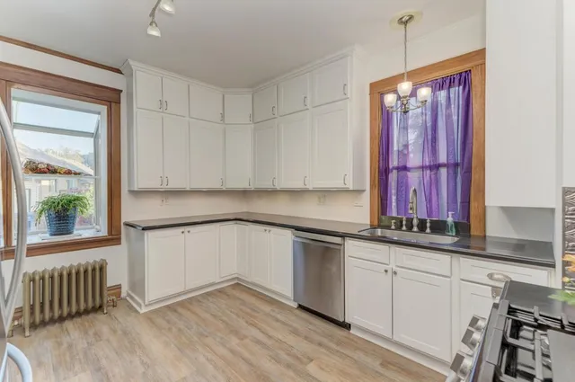 a kitchen with stainless steel appliances granite countertop a stove a sink and white cabinets