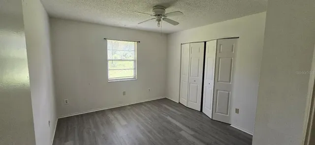 an empty room with wooden floor ceiling fan and windows